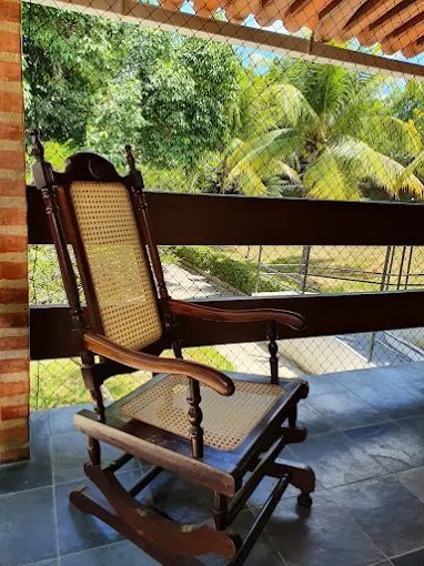 Varanda acolhedora com cadeira de balanço e vista para o jardim